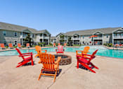 Thumbnail 1 of 39 - A pool surrounded by red chairs and buildings in the background. at The Lory of Greenway Village Apartments, Ky