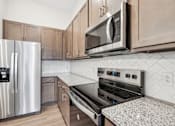 Thumbnail 15 of 28 - A modern kitchen with a stainless steel refrigerator, microwave, and oven.at The Parker Leland, Leland, NC 28451  