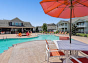 Thumbnail 29 of 39 - A large orange umbrella is in the foreground of a pool area. at The Lory of Greenway Village Apartments, Ky