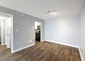 Thumbnail 6 of 15 - an empty living room with wood flooring and a door to a kitchen  at Governors House, Huntsville, 35805