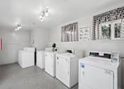 Thumbnail 7 of 24 - A laundry room with washing machines and a window.