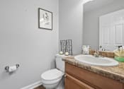 Thumbnail 17 of 24 - A bathroom with a toilet, sink, and a picture on the wall.