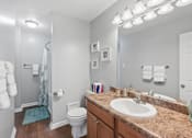 Thumbnail 9 of 24 - A bathroom with a toilet, sink, and mirror.
