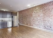 Thumbnail 6 of 50 - a living room with a brick wall and a kitchen with stainless steel appliances
