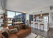 Thumbnail 11 of 50 - a living room with a couch and a kitchen with a bar