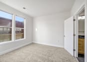 Thumbnail 24 of 64 - A room with a carpeted floor and a door leading to a kitchen.