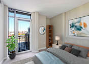 Thumbnail 14 of 50 - a bedroom with a bed and a sliding glass door to a balcony