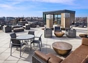 Thumbnail 45 of 50 - a rooftop terrace with couches tables and chairs and views of the city