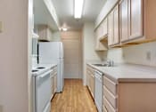 Thumbnail 4 of 17 - A kitchen with white appliances and wooden floors.