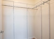 Thumbnail 25 of 37 - a walk in closet with white walls and a metal rack on the wall