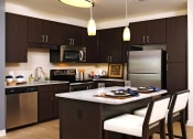 Thumbnail 3 of 47 - a kitchen with stainless steel appliances and a island with chairs