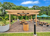Thumbnail 20 of 32 - a wooden pergola with benches and tables in a park