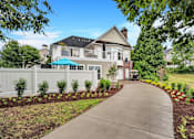Thumbnail 24 of 32 - a large white house with a gray roof and a gray sidewalk in front of it