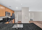 Thumbnail 3 of 32 - A kitchen with a black granite countertop and wooden cabinets.