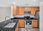 Thumbnail 1 of 32 - A kitchen with a black granite countertop and wooden cabinets.