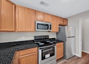 Thumbnail 2 of 32 - A kitchen with wooden cabinets and a black countertop.