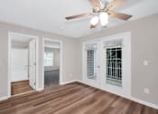 Thumbnail 7 of 32 - A room with a ceiling fan and wooden floors.