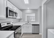Thumbnail 20 of 25 - a white kitchen with a stove and a microwave