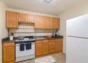 Thumbnail 4 of 15 - a kitchen with white appliances and wooden cabinets and a refrigerator