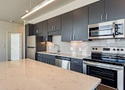 Thumbnail 14 of 37 - an empty kitchen with black cabinets and a white counter top