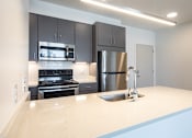 Thumbnail 16 of 37 - a kitchen with a white counter top and a stainless steel refrigerator