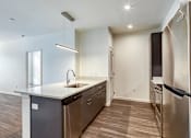 Thumbnail 17 of 37 - an empty kitchen with stainless steel appliances and wood flooring