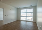 Thumbnail 23 of 37 - an empty living room with wood floors and a large window