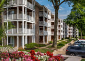 Thumbnail 22 of 23 - a picture of an apartment complex with trees and flowers in the foreground
