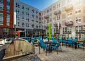 Thumbnail 2 of 37 - a patio with blue chairs and tables in front of an apartment building