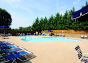 Thumbnail 11 of 17 - A pool with blue chairs and a blue umbrella.