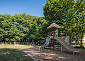 Thumbnail 5 of 14 - A playground with a slide and a wooden structure.