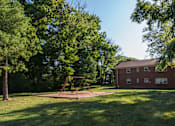 Thumbnail 13 of 14 - A playground with a swing set in a grassy area in front of a red brick house.