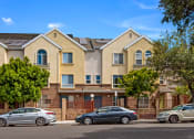 Thumbnail 1 of 4 - a row of apartment buildings with cars parked in front of them