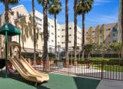 Thumbnail 3 of 4 - a playground with a slide in front of an apartment building