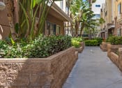 Thumbnail 4 of 4 - a walkway between two apartment buildings with bushes and plants