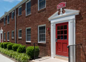 Thumbnail 1 of 12 - a brick apartment building with a red door at Clarendon Court