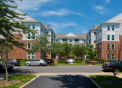 Thumbnail 3 of 12 - an apartment building with cars parked in front of it