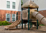 Thumbnail 5 of 12 - a playground with a slide and a playset in front of a brick building