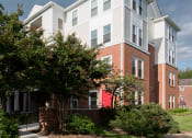 Thumbnail 4 of 12 - Clarendon Court Apartments building with a courtyard with bushes and trees