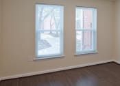 Thumbnail 10 of 12 - an empty bedroom with two windows and wood flooring