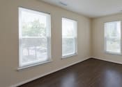 Thumbnail 9 of 12 - an empty bedroom with wood floors and three windows