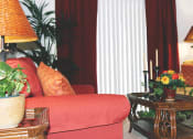 Thumbnail 6 of 6 - a living room with a red couch and a table with flowers at Senior Living at Henson Village