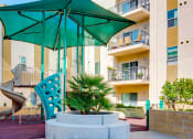 Thumbnail 5 of 10 - a playground at Santa Cecilia Apartments with a large green umbrella