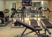 Thumbnail 5 of 6 - a gym with cardio equipment and a tv on the wall