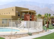 Thumbnail 1 of 6 - Vista Sunrise Apartments clubhouse with a pool behind a fence