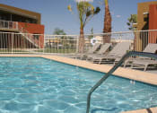 Thumbnail 2 of 6 - a swimming pool at Vista Sunrise Apartments with chairs and a fence