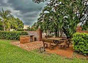 Thumbnail 1 of 24 - A patio with a table and chairs surrounded by greenery.