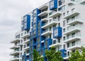 Thumbnail 6 of 24 - A tall residential building with balconies and windows.