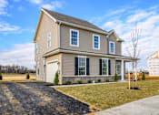 Thumbnail 5 of 20 - Exterior of tan 2 story cottage with garage