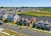 Thumbnail 2 of 23 - A suburban street with houses on both sides and a car parked on the side of the road.